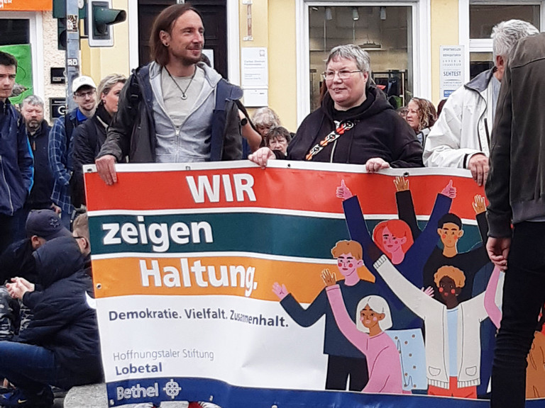Teilnehmende des Protestmarsches halten ein Banner mit der Aufschrift Wir zeigen Haltung