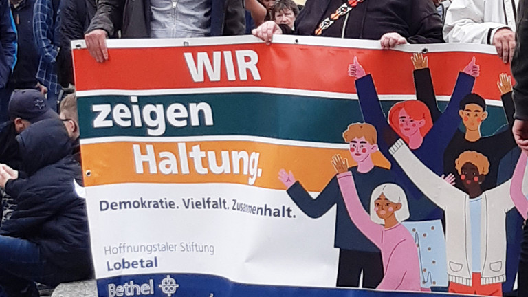 Teilnehmende des Protestmarsches halten ein Banner mit der Aufschrift Wir zeigen Haltung Teilnehmende des Protestmarsches halten ein Banner mit der Aufschrift Wir zeigen Haltung