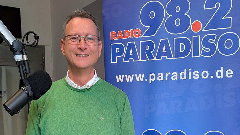 Ralf Schäfer, Beauftragter für Diversität und queere Lebensweisen der Immanuel Albertinen Diakonie, Sparte Wohnen und Pflegen, im Studio von Radio Paradiso vor einem Mikrofon, Vielfalt in der Pflege, LGBTQ, queersensible Pflege Ralf Schäfer, Beauftragter für Diversität und queere Lebensweisen der Immanuel Albertinen Diakonie, Sparte Wohnen und Pflegen, im Studio von Radio Paradiso vor einem Mikrofon