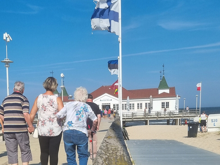 Pflegekraft mit Bewohner und Bewohnerin auf der Seebrücke