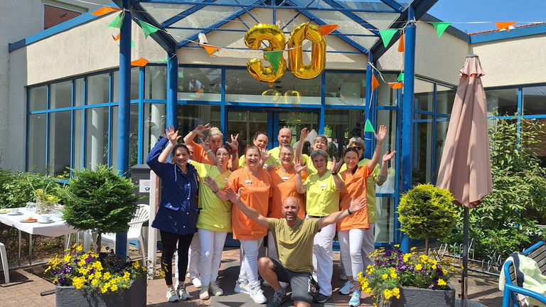 Gruppenbild des Teams vor dem Eingang mit einem 30 Ballon - Immanuel Haus Ecktannen in Waren