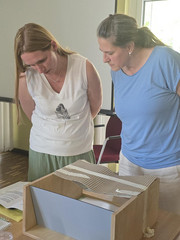 Zwei Mitarbeiterinnen der Immanuel Miteinander Leben blicken bei einer Fortbildung zum Thema Demenz auf einen Tisch und lesen die begleitenden Texte einer Infostation Zwei Mitarbeiterinnen der Immanuel Miteinander Leben blicken bei einer Fortbildung zum Thema Demenz auf einen Tisch und lesen die begleitenden Texte einer Infostation