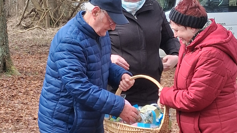 Seniorinnen und Senioren aus der Tagespflege bei einem Osterspaziergang im Wald mit gefülltem Osterkörbchen