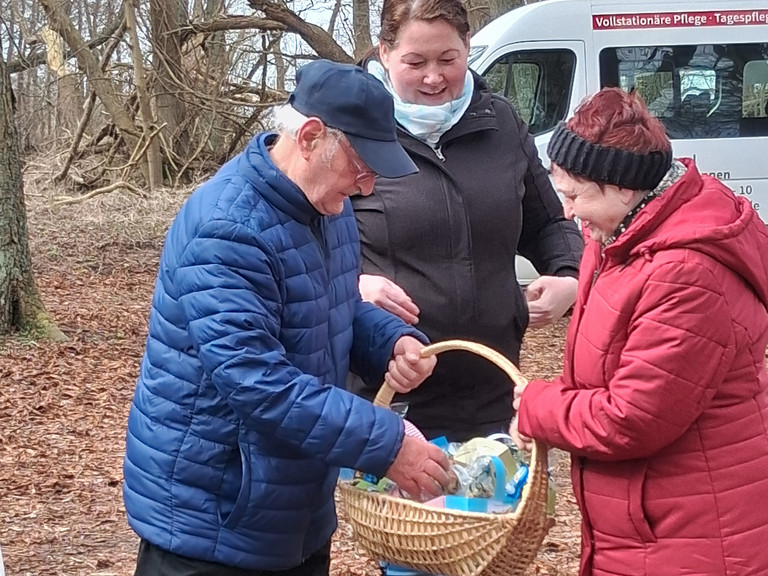 Seniorinnen und Senioren aus der Tagespflege bei einem Osterspaziergang im Wald mit gefülltem Osterkörbchen