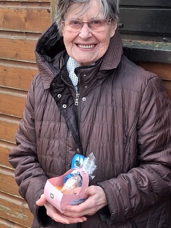 Seniorin aus der Tagespflege zeigt ein selbst gestaltetes Osterkörbchen mit Ostergeschenken