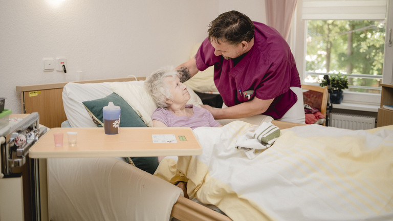 Ein Pfleger unterhält sich mit einer Seniorin im Pflegezimmer im Seniorenzentrum Kläre Weist in Petershagen