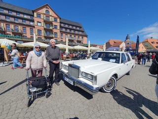 Zwei Bewohner des Immanuel Haus Ecktannen stehen auf einem Platz neben einem weißen alten Mercedes
