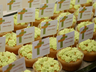 Zahlreiche Muffins mit grün-gelber Zuckerdekoration und Papierfähnchen mit dem Logo und Namen der Einrichtung bei der Wiedereröffnung der Tagespflegestätte für ältere Menschen im Immanuel Seniorenzentrum Kläre Weist in Petershagen