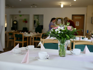 Blick auf einen festlichen gedeckten Tisch mit weißen Servietten und einer Blumenvase mit einem Blumenstrauß bei der Wiedereröffnung der Tagespflegestätte für ältere Menschen „Kläre Weist“ in Petershagen