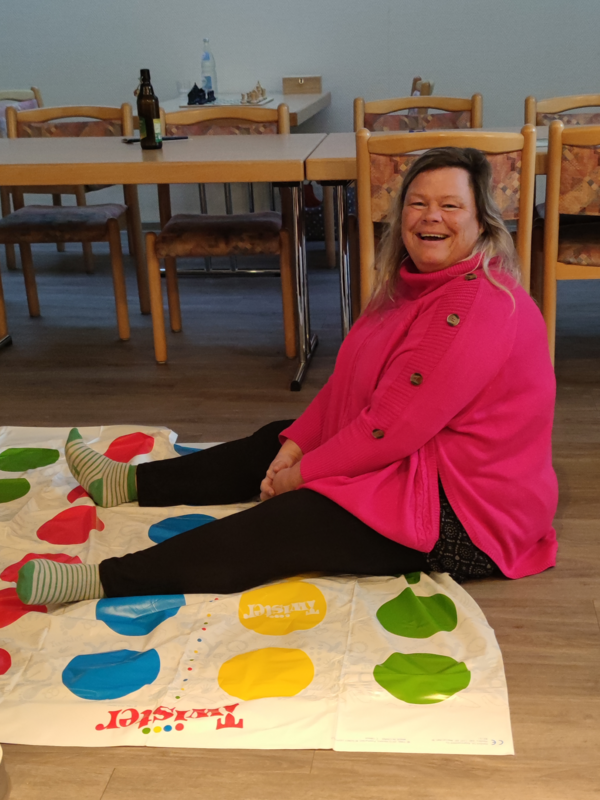 Eine Mitarbeiterin sitzt lachend auf einer Spieldecke in der Immanuel Begegnungsstätte Ecktannen im Heilbad Waren beim gemeinsamen Spieleabend für Mitarbeitende der Seniorenpflegeeinrichtung mit Tagespflegeangebot Immanuel Haus Ecktannen. Eine Mitarbeiterin sitzt lachend auf einer Spieldecke in der Immanuel Begegnungsstätte Ecktannen im Heilbad Waren beim gemeinsamen Spieleabend für Mitarbeitende der Seniorenpflegeeinrichtung mit Tagespflegeangebot Immanuel Haus Ecktannen.