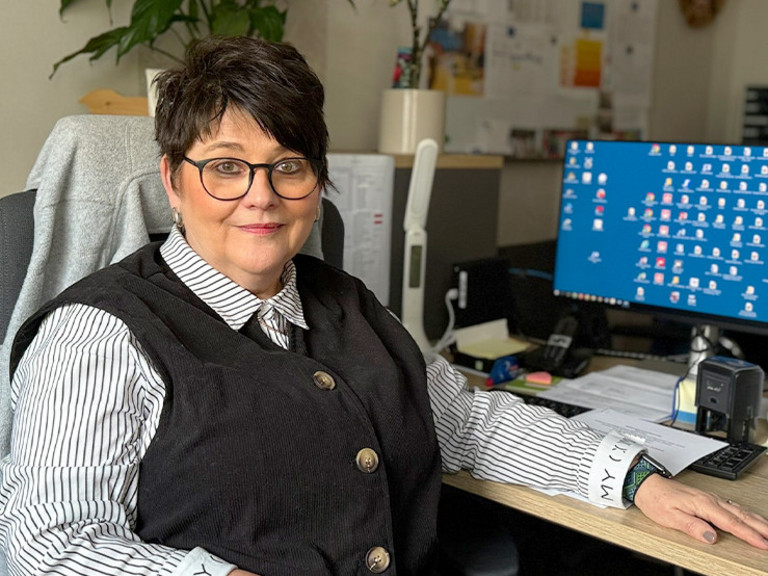 Marion Swietza, Leiterin „Besondere Wohnform“ sowie des ambulanten Bereichs beim Immanuel Suchthilfeverbund Guben, sitzt in ihrem Büro am Schreibtisch vor einem Monitor und blickt in die Kamera.